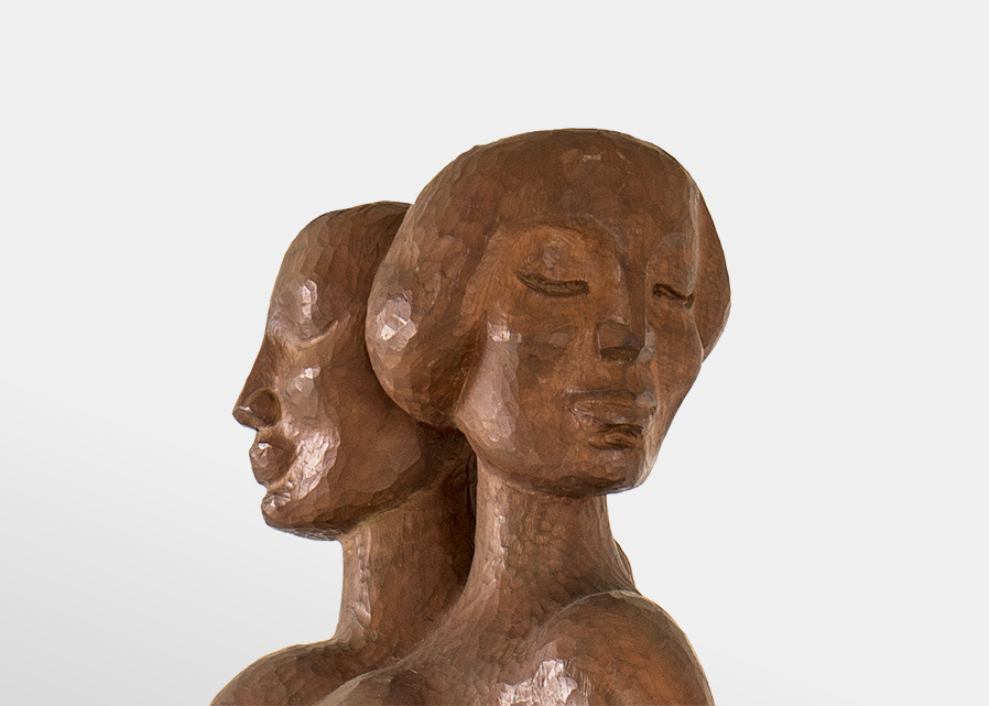 Two serene women's heads, carved out of shining wood.