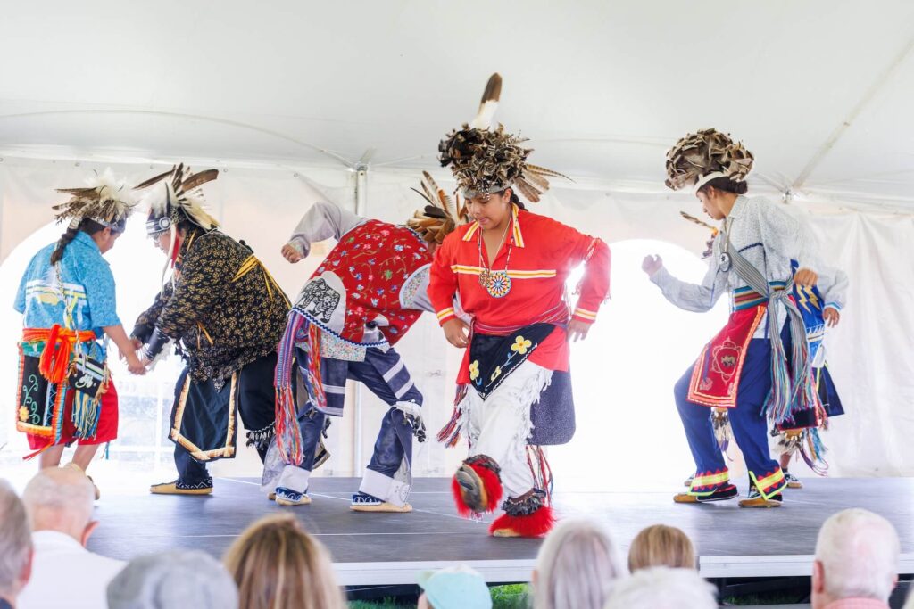 The Allegany River Seneca Dancers performing on a stage.