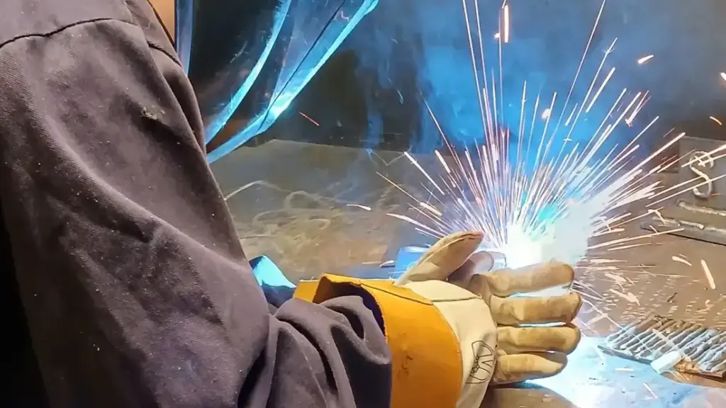 A person welding metal, sparks flying up.