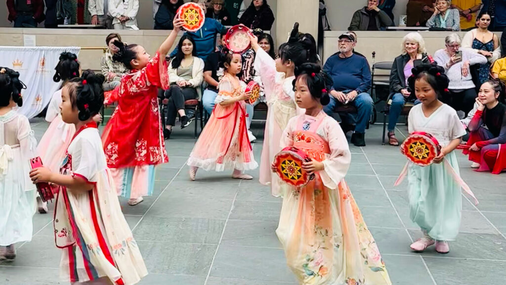 Young girls in East Asian clothing doing a dance in the Vanden Brul Pavilion.