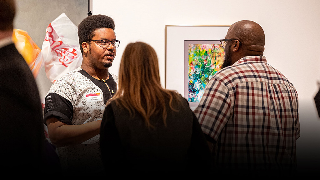 Unique Fair-Smith talking to people in MAG's Docent Gallery.