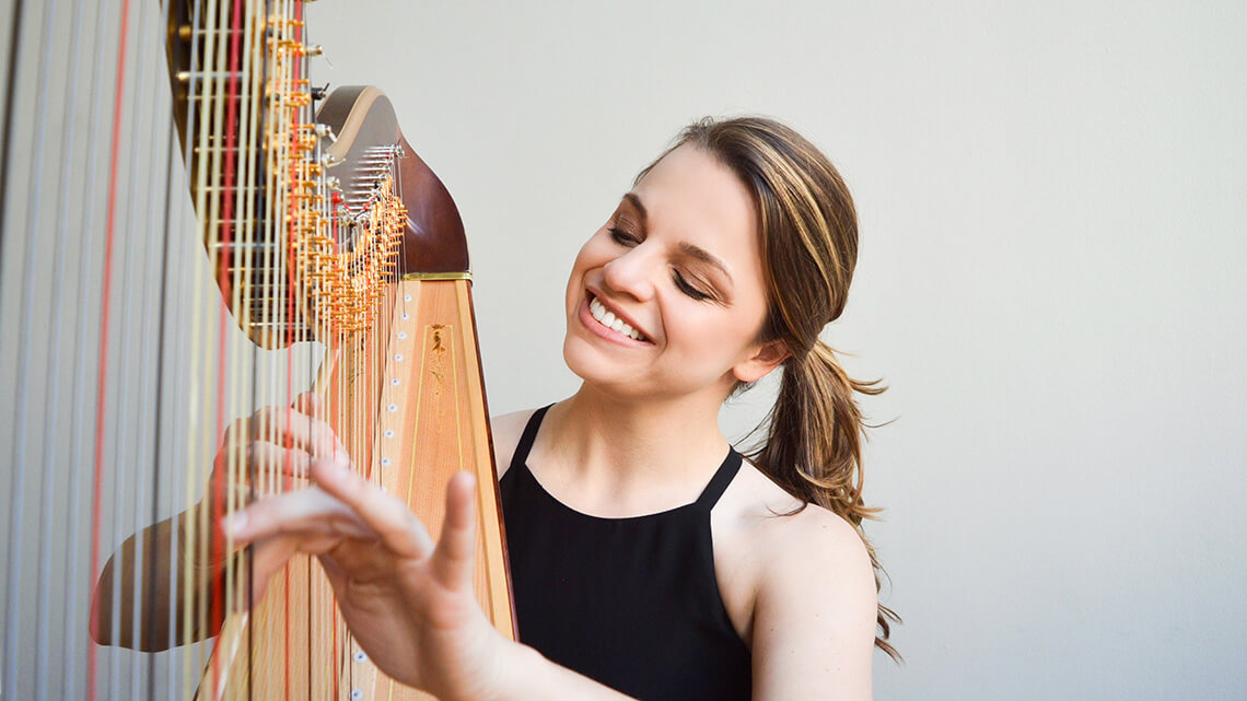 Grace Browning smiling and playing the harp.