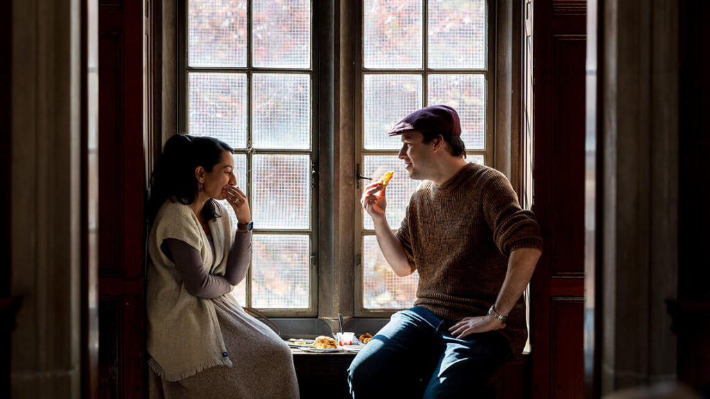 Two members laughing and sitting in a window at one of MAG's opening parties.