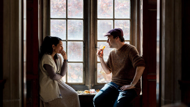 Two members laughing and sitting in a window at one of MAG's opening parties.