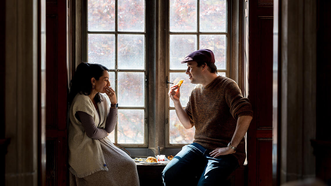 Two members laughing and sitting in a window at one of MAG's opening parties.