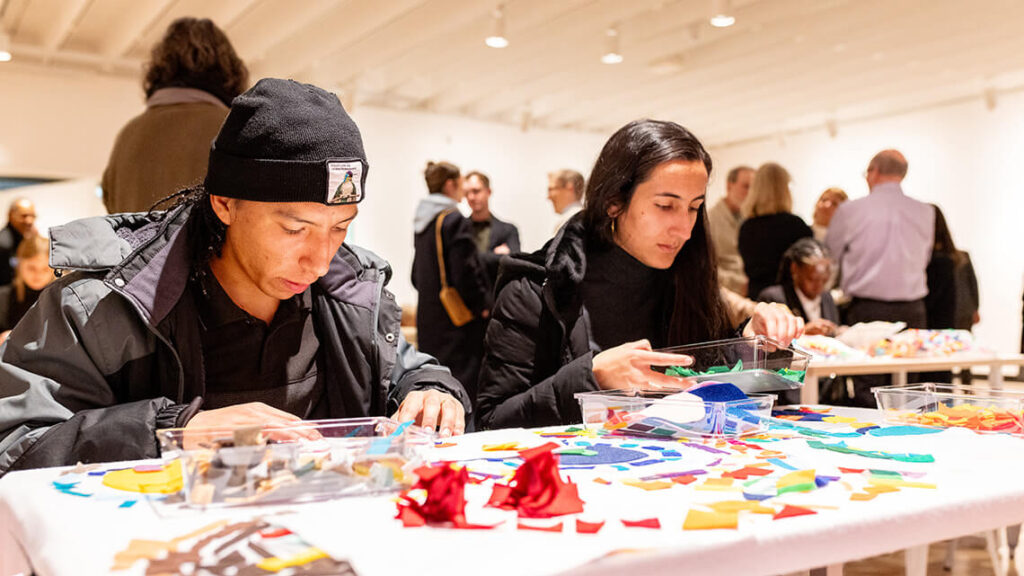 Two adults working on a colorful art project at a table together.
