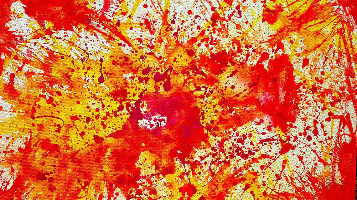 A splatter painting done in yellow, red, and orange paint.