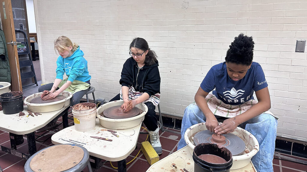 Three teen girls working on the potter's wheel in MAG's ceramic studios.