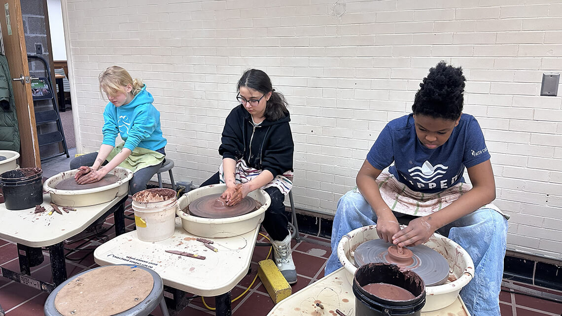 Three teen girls working on the potter's wheel in MAG's ceramic studios.
