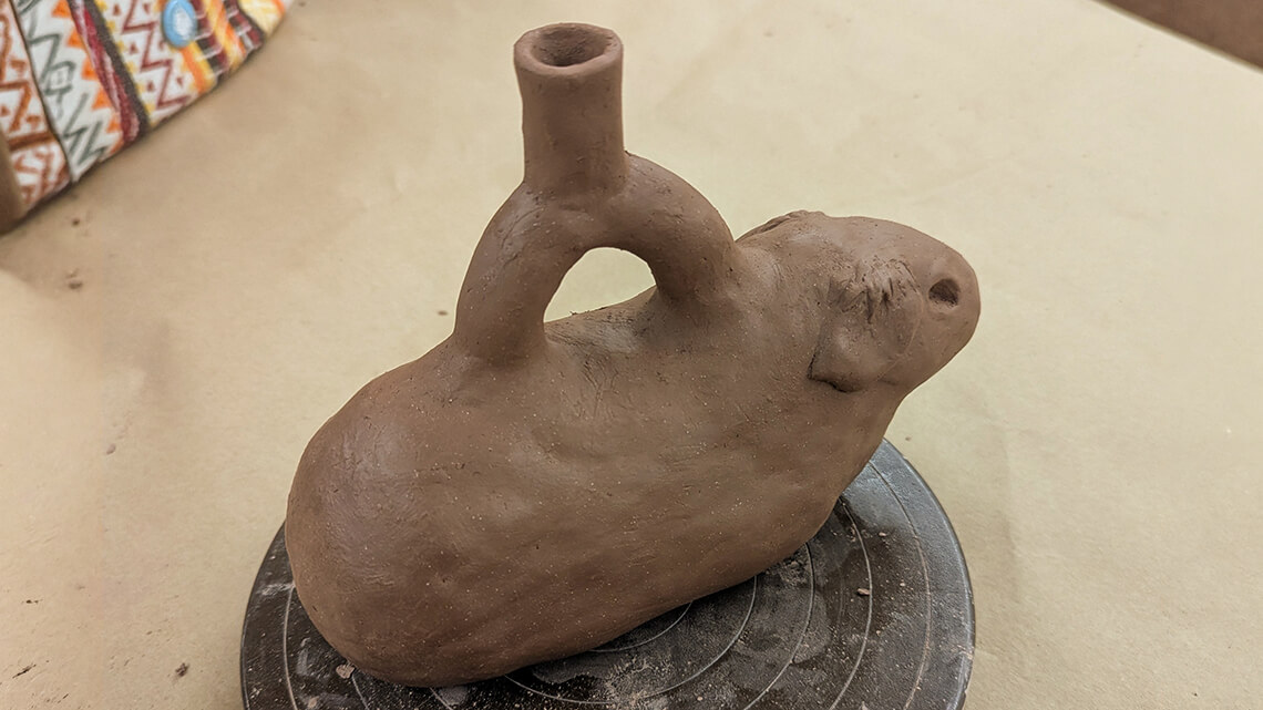 A small vessel shaped like a hamster with a spout at the top.