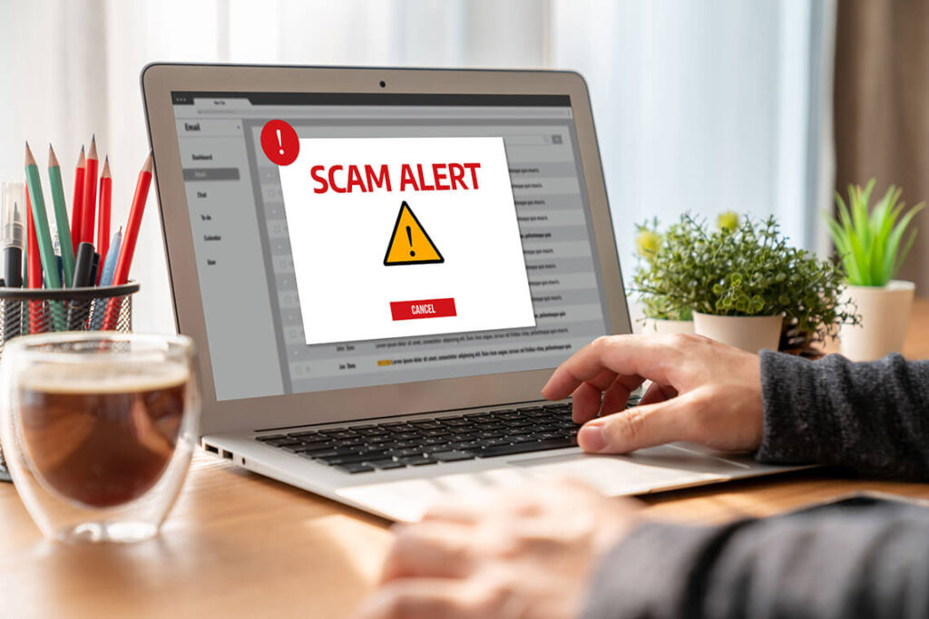A laptop screen with a window open on it reading "scam alert."