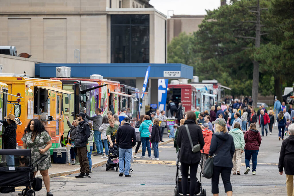 Clothesline visitors browsing a line of food trucks.