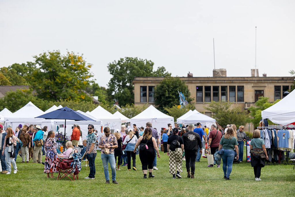 A crowd of visitors on MAG's lawn browsing artist booths at Clothesline.