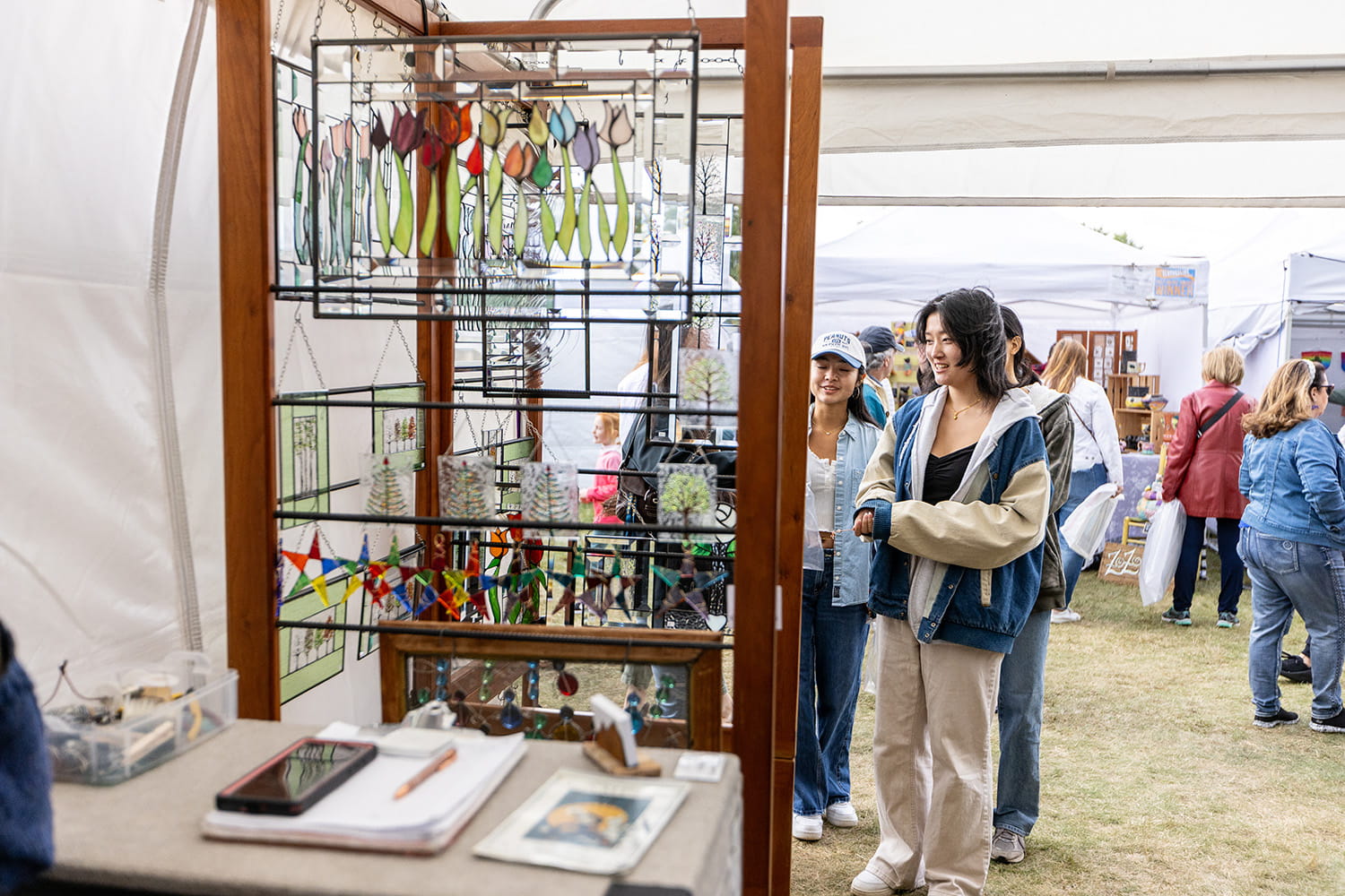 Visitors browse a booth of glass art at Clothesline.
