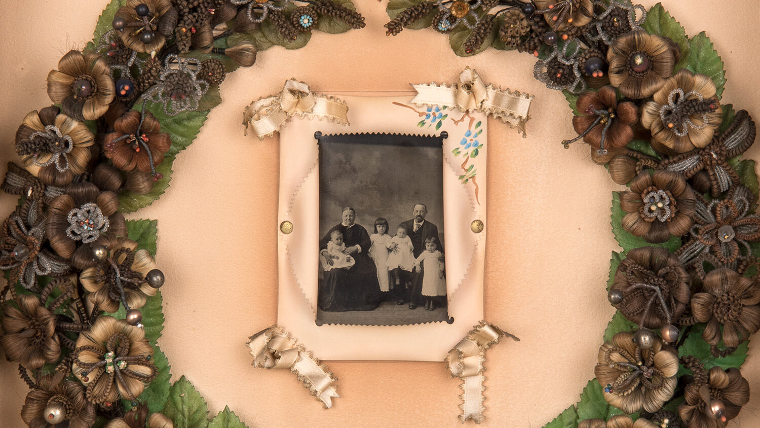 A back and white photograph surrounded by a wreath of flowers made of hair.