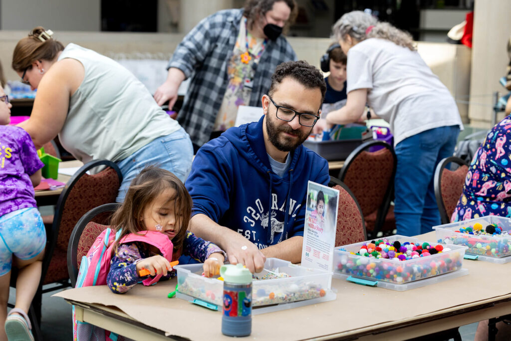 A father and daughter doing a craft in the Vanden Brul Pavilion.