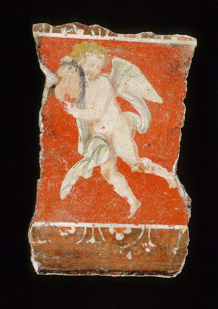 Fragment of a plaster fragment showing a flying cupid against a brilliant rust-red background.