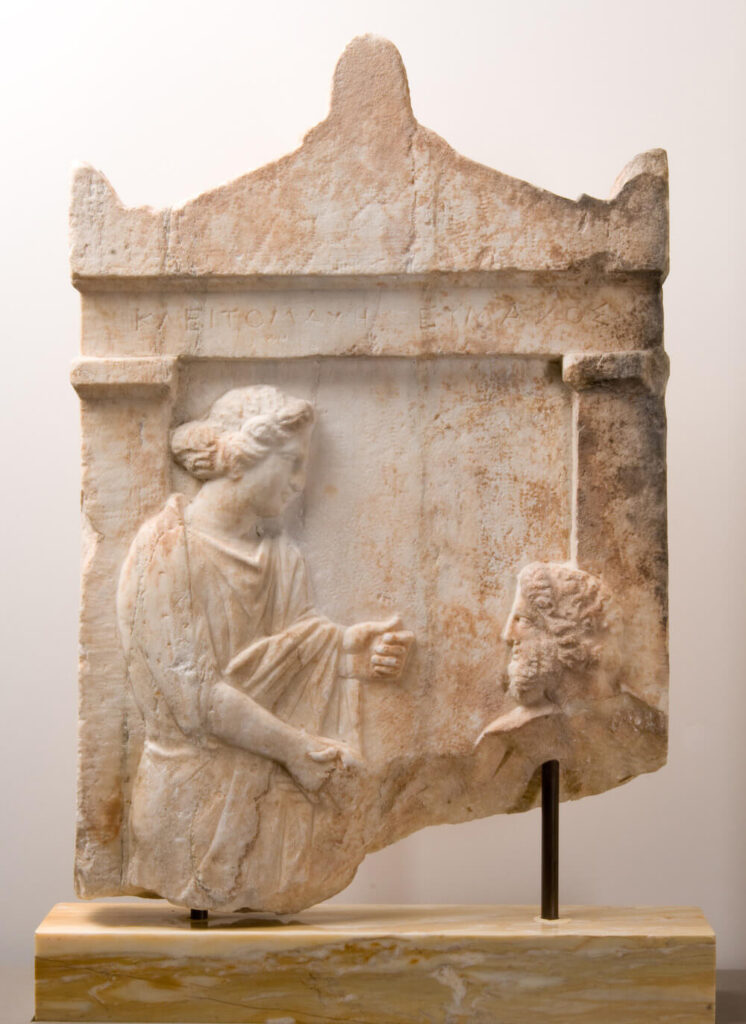 Marble gravestone depicting a handshake between a husband and wife.