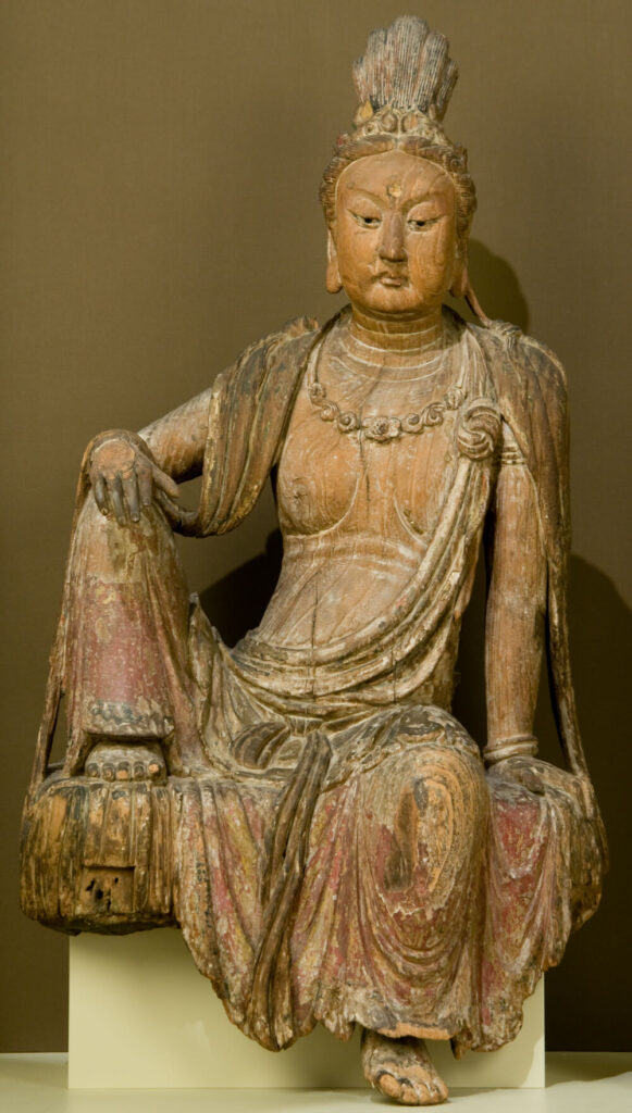 Guanyin Bodhisattva seated with one leg drawn up, elbow resting on it.