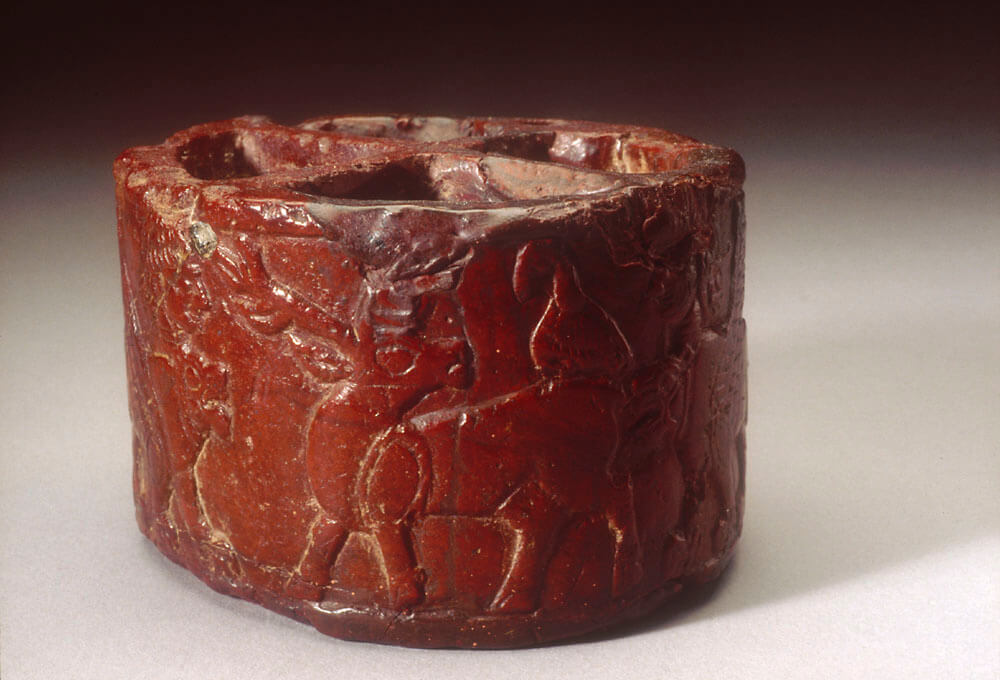 Red stone toiletry box engraved with animals, natural and mythological.