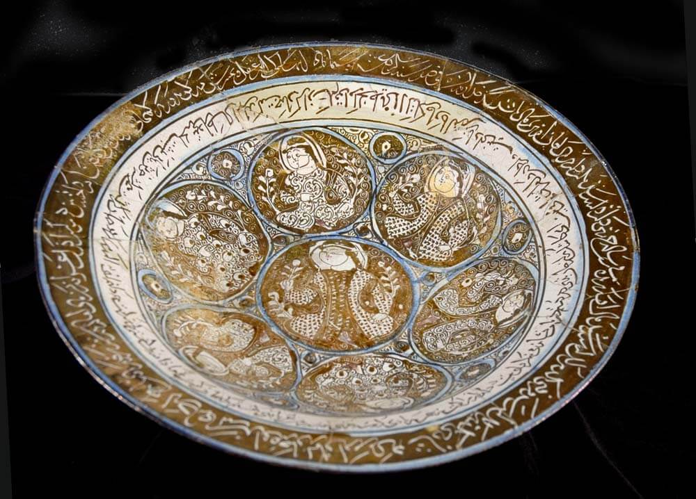 Lustre glazed ceramic bowls with an Arabic inscription surrounding roundels with figures in them.