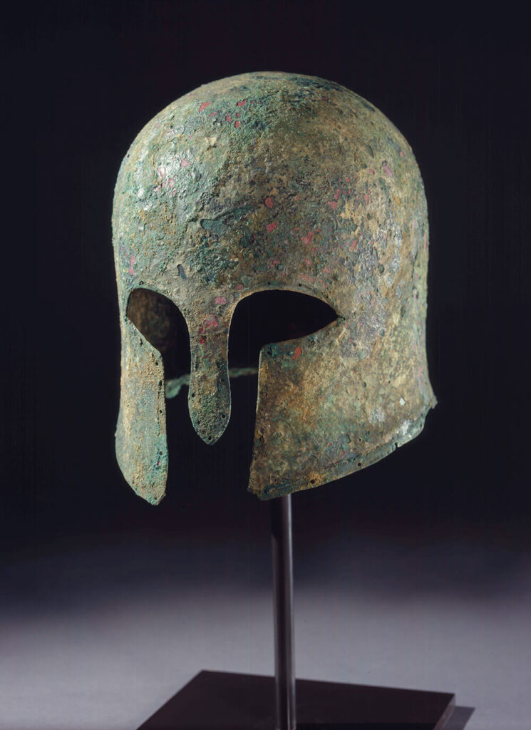 Bronze Greek helmet with a rusted green patina.
