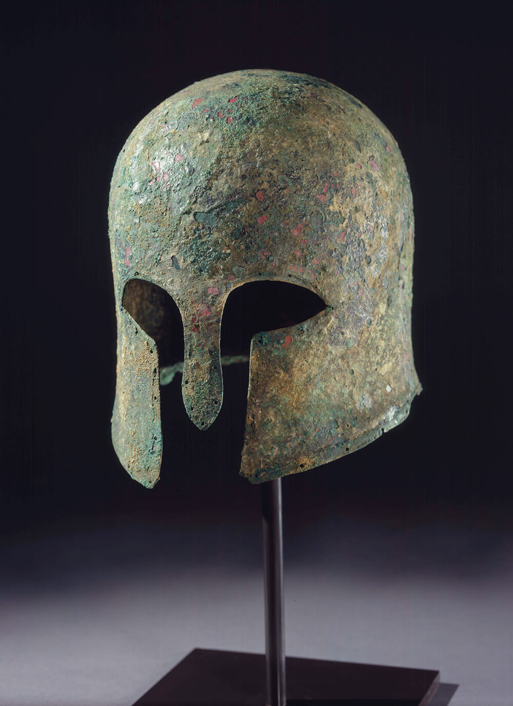 Bronze Greek helmet with a rusted green patina.