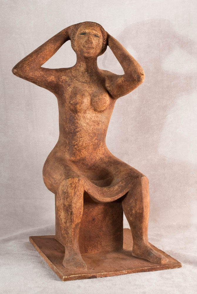 Terracotta sculpture of a sitting woman fixing her hair.