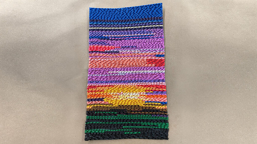 A vertical landscape of a sunset, made entirely out of spirals of colored paper.