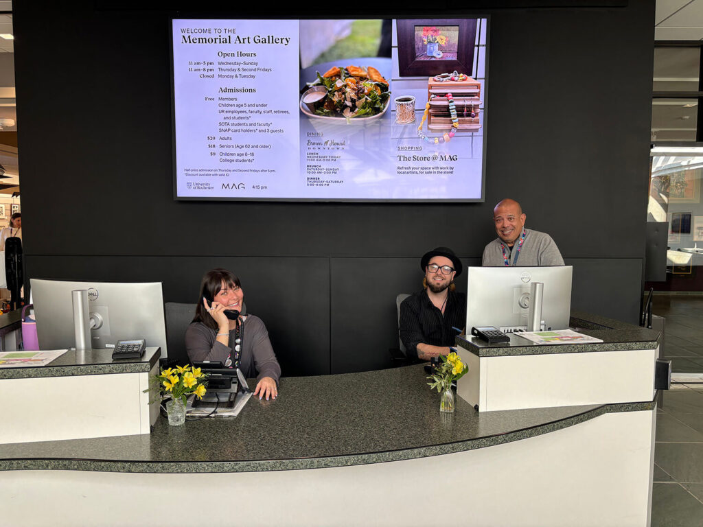 Guest Services staff smiling and working at the Admissions Desk.