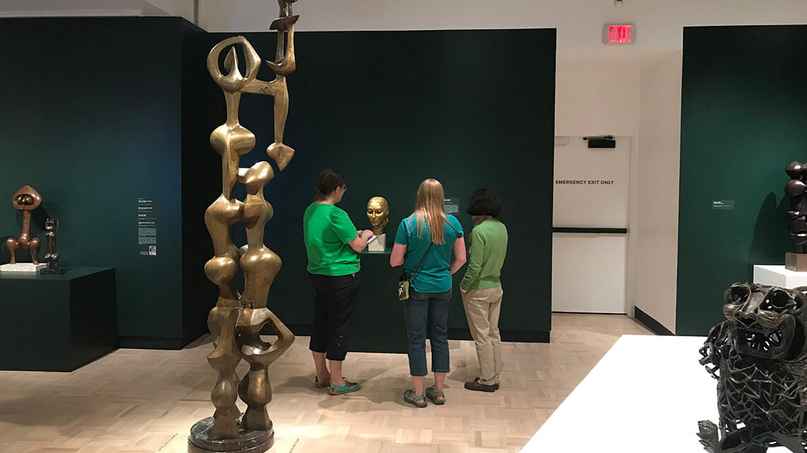 Teachers looking at John Rhoden's sculpture in MAG's Docent Gallery.