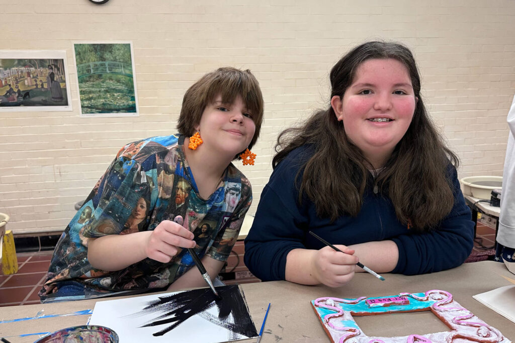 Teen girls painting ceramic frames in a Creative Workshop camp.