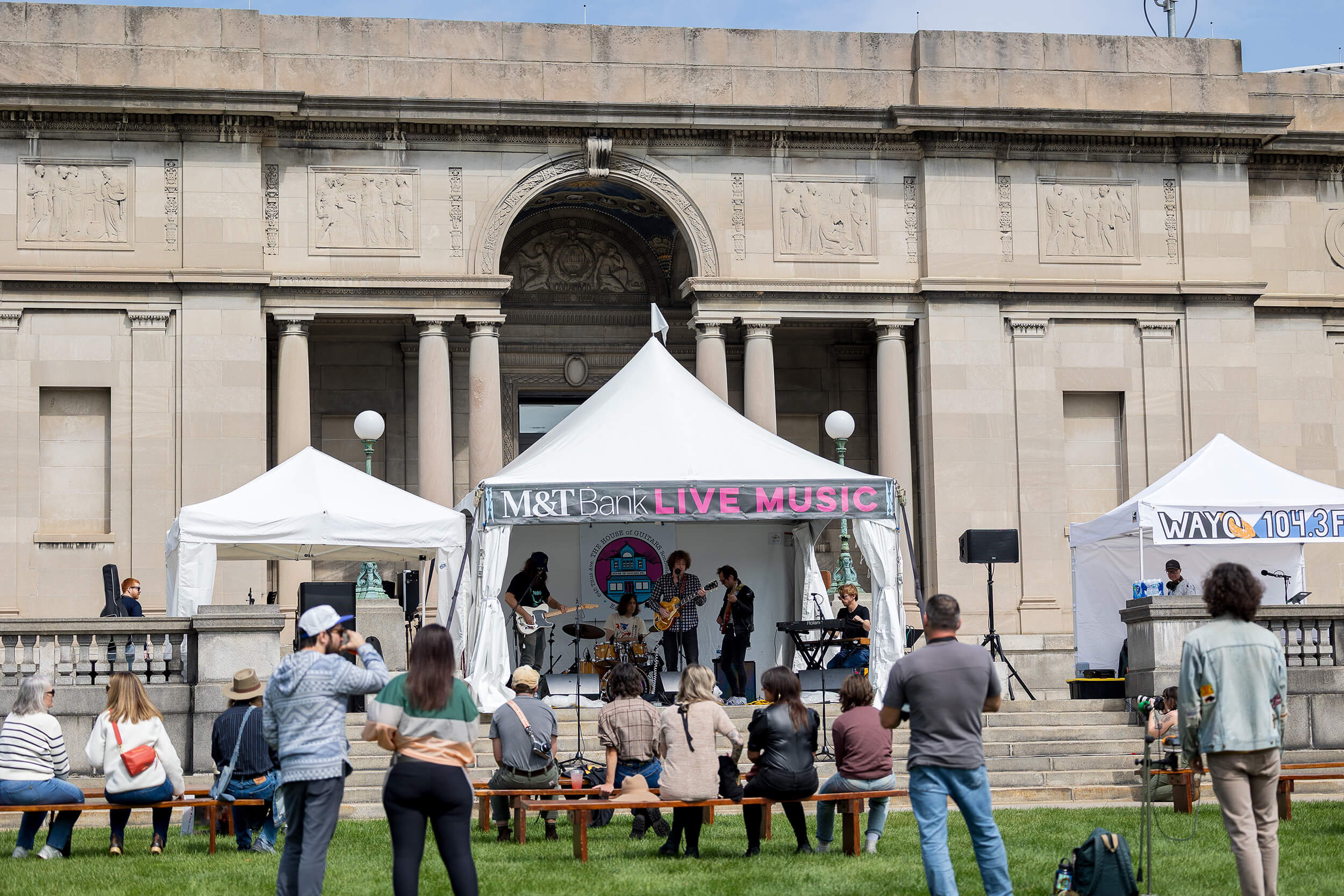People listen to a band playing in the M&T Bank live music tent at the 2025 Clothesline Festival.