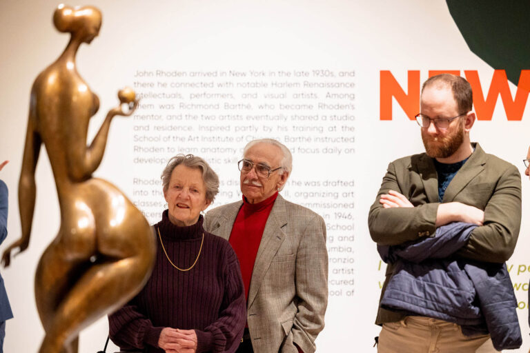 People looking at sculpture in the exhibition "Determined to Be: The Sculpture of John Rhoden."