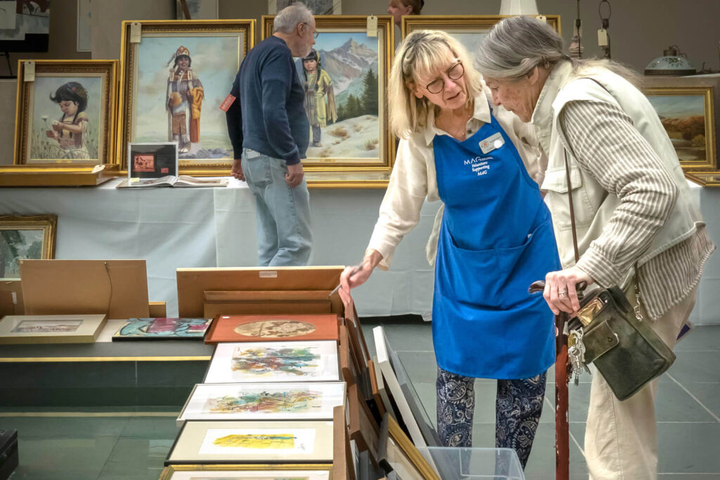 A MAG Council volunteer helping a visitor at the 2024 Art & Treasures Sale.