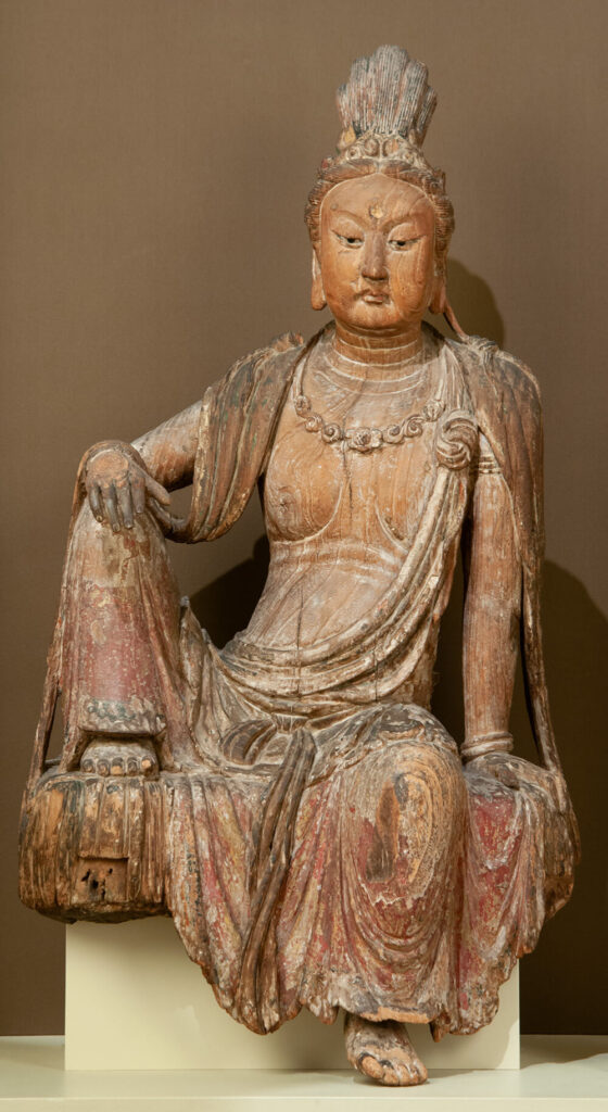 Guanyin Bodhisattva seated with one leg drawn up, elbow resting on it.