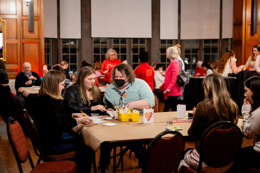 People sitting and doing crafts at tables set up in the Bausch & Lomb Parlor.