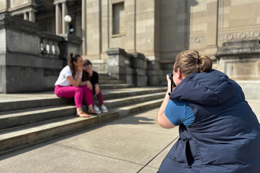 A photographer taking pictures of two people on the steps of MAG's 1913 building.