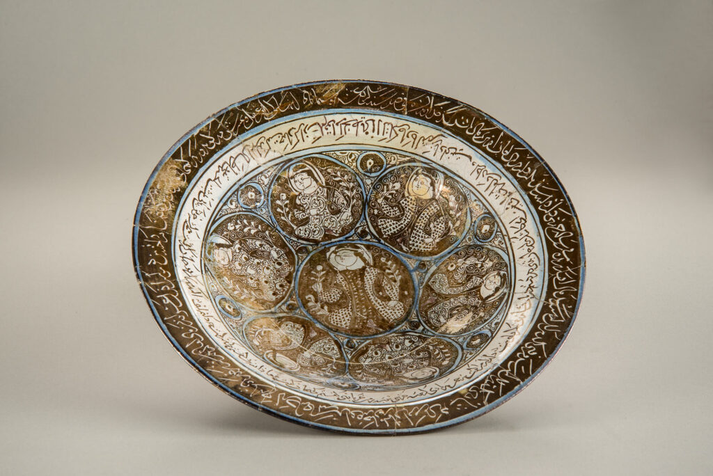 Lustre glazed ceramic bowls with an Arabic inscription surrounding roundels with figures in them.