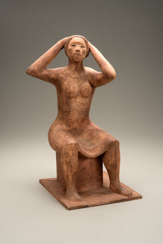 Terracotta sculpture of a sitting woman fixing her hair.