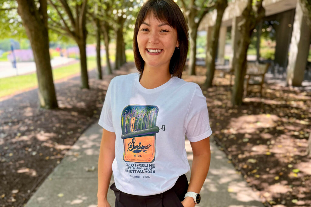 A woman wearing a white tee with a colorful painting of sardines on it.