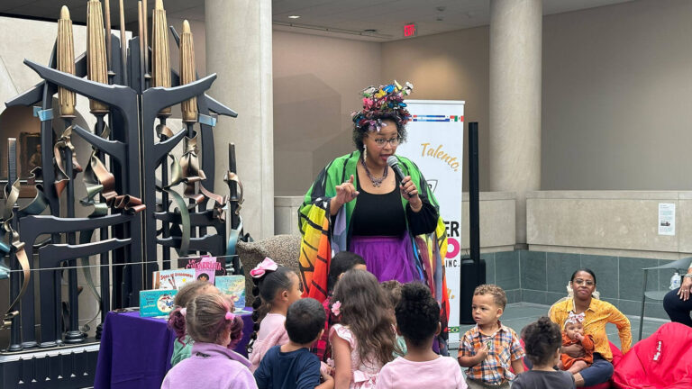 Storyteller Ms. Mariposa reading to children in the Vanden Brul Pavilion.