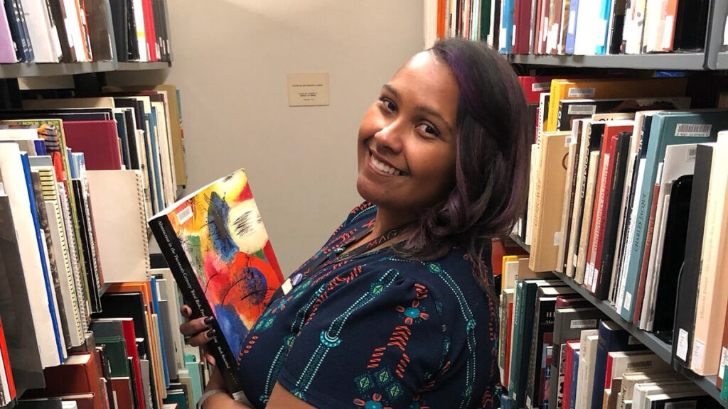Eboni Jones smiling in the stacks of the library.